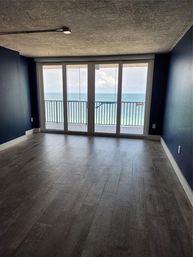 spare room featuring plenty of natural light, a water view, and dark wood-style floors