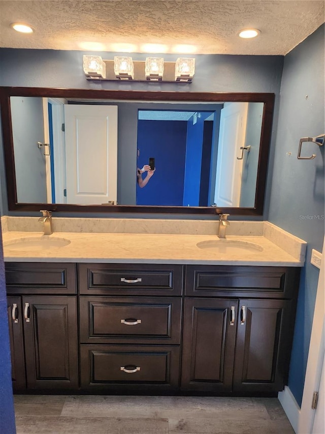 full bath featuring a sink, double vanity, and a textured ceiling