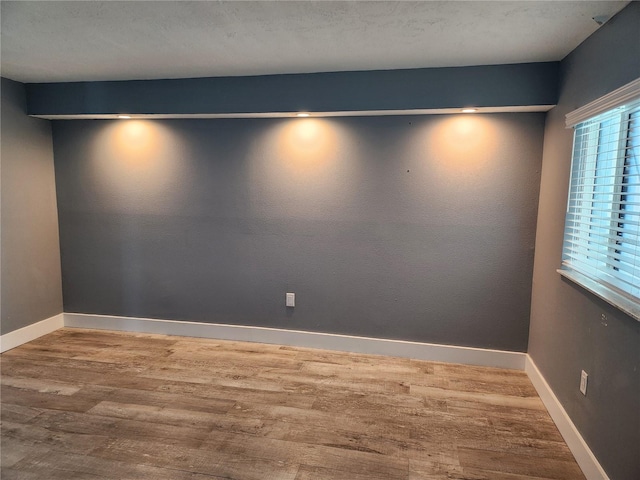 spare room featuring baseboards and wood finished floors