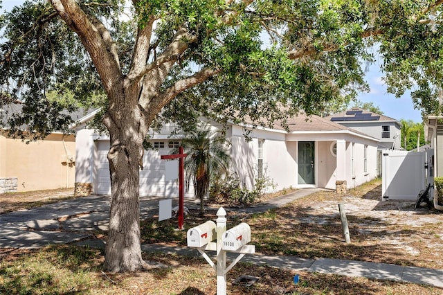 view of front of property with driveway, stucco siding, an attached garage, and fence