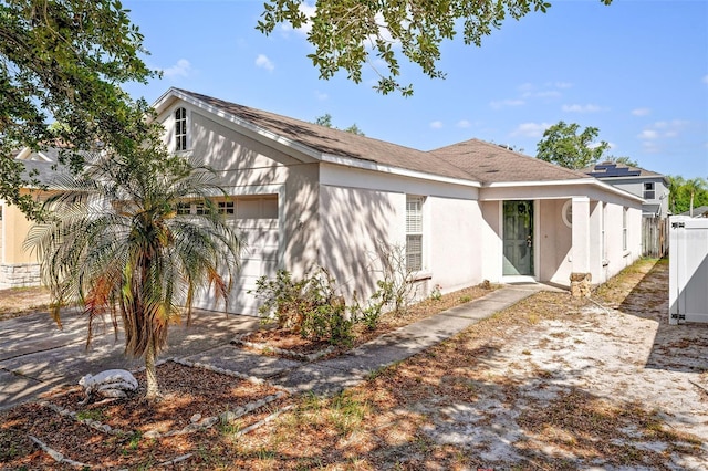 view of front of house featuring driveway, stucco siding, an attached garage, and fence