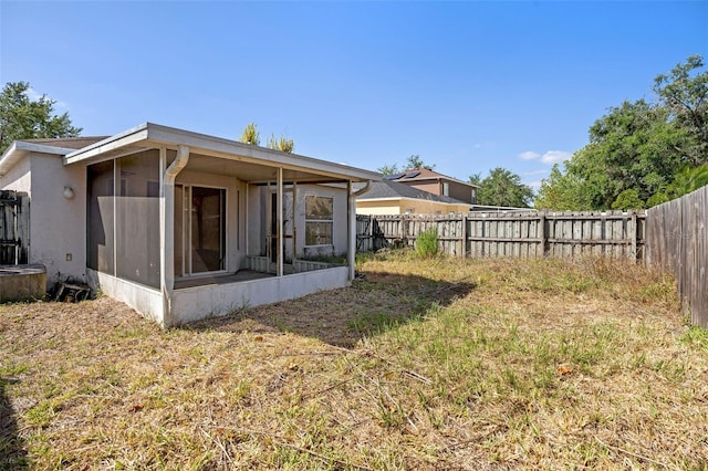 rear view of house with a fenced backyard and a sunroom