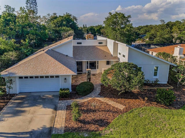 833 Lakeside Ter, Palm Harbor, FL 34683 - mid-century inspired home with a garage, a shingled roof, a chimney, and concrete driveway