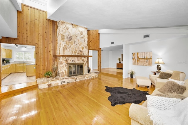 833 Lakeside Ter, Palm Harbor, FL 34683 - living area featuring visible vents, a fireplace, wood walls, lofted ceiling, and light wood-style floors