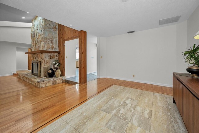 833 Lakeside Ter, Palm Harbor, FL 34683 - living room with visible vents, lofted ceiling, baseboards, a stone fireplace, and light wood-type flooring