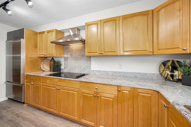 833 Lakeside Ter, Palm Harbor, FL 34683 - kitchen with wall chimney range hood, light stone countertops, black electric cooktop, built in refrigerator, and light wood finished floors