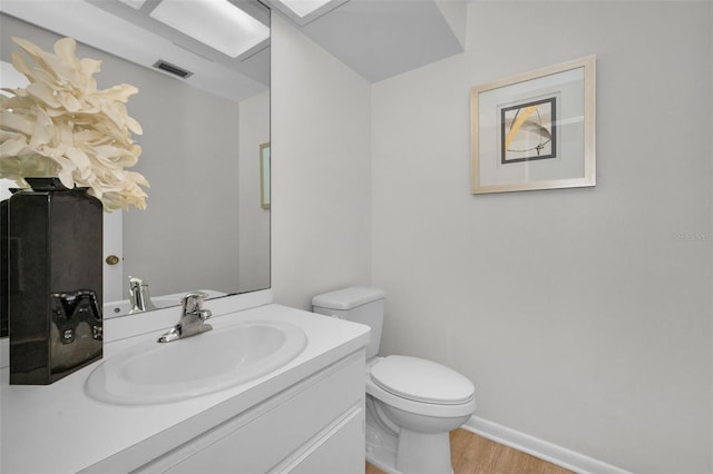 833 Lakeside Ter, Palm Harbor, FL 34683 - half bathroom featuring visible vents, vanity, wood finished floors, toilet, and baseboards