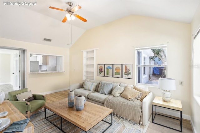 living area featuring wood finished floors, a ceiling fan, visible vents, baseboards, and vaulted ceiling