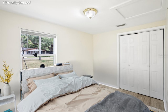 bedroom featuring a closet, attic access, visible vents, and wood finished floors