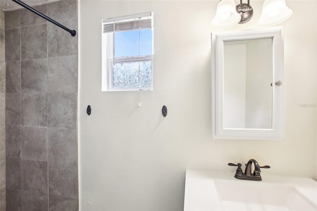 bathroom with a tile shower, an inviting chandelier, and a sink