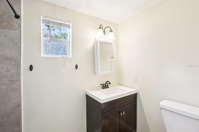 full bathroom with toilet, vanity, a shower, and a textured ceiling