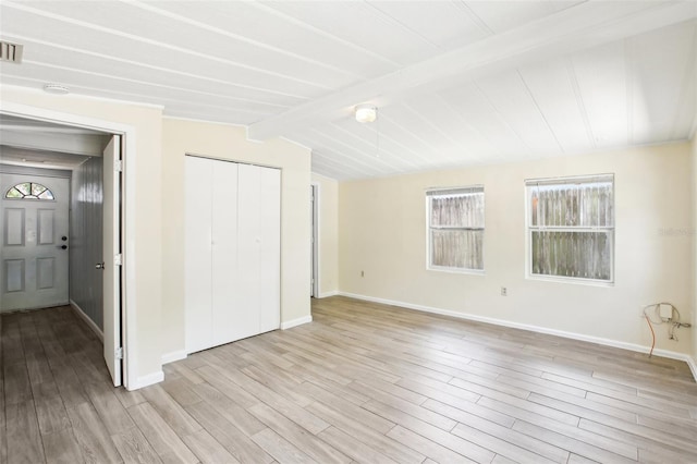 unfurnished bedroom with a closet, vaulted ceiling with beams, light wood-type flooring, visible vents, and baseboards