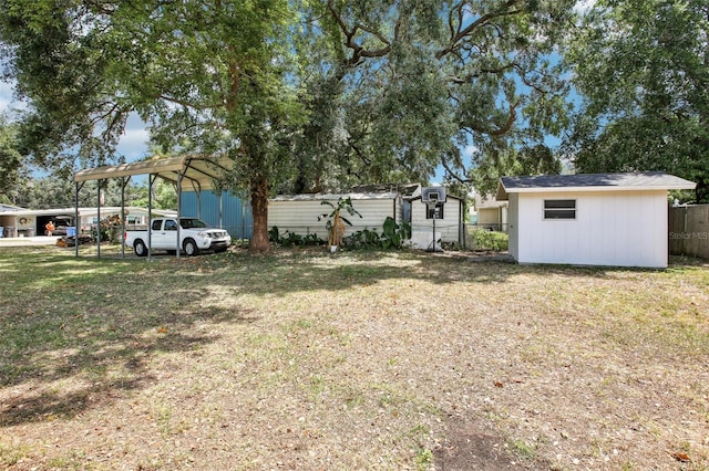 view of yard featuring a detached carport, fence, and an outdoor structure