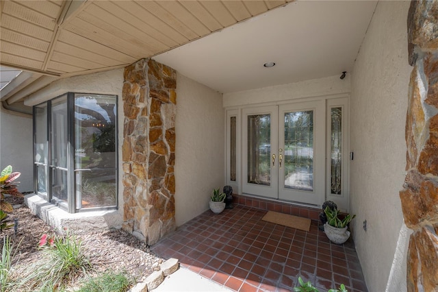 property entrance featuring stucco siding, french doors, and stone siding