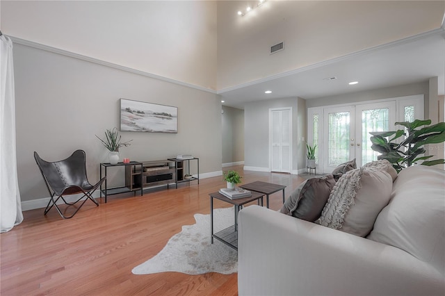 living room featuring visible vents, a towering ceiling, recessed lighting, french doors, and light wood finished floors