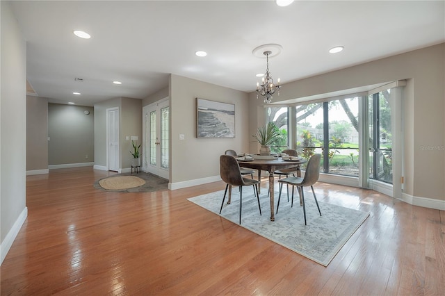 dining area with recessed lighting, baseboards, an inviting chandelier, and light wood-style floors