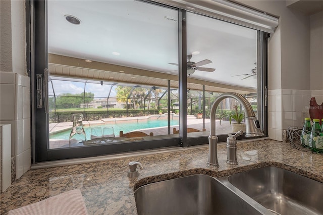 details with dark stone counters, ceiling fan, and a sink