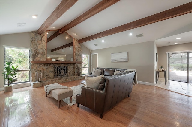 living area featuring visible vents, lofted ceiling with beams, light wood-style flooring, and plenty of natural light
