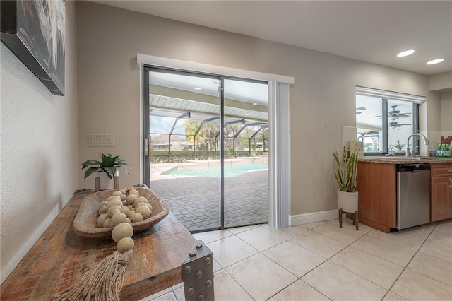 doorway to outside featuring a sink, light tile patterned floors, recessed lighting, and a healthy amount of sunlight
