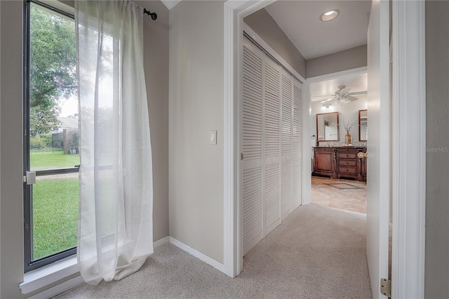 hall with baseboards and light carpet