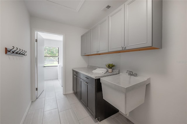 interior space featuring a sink, baseboards, light tile patterned flooring, and visible vents
