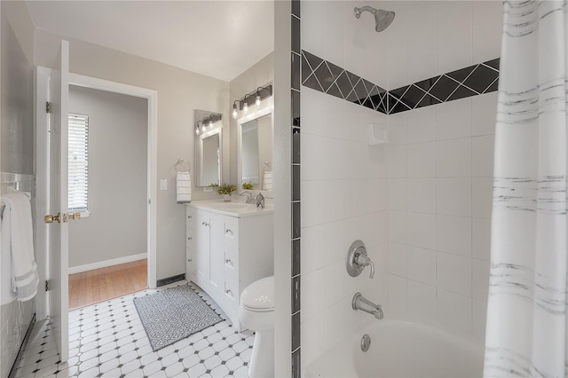 bathroom featuring vanity, toilet, baseboards, tile patterned floors, and shower / bath combo