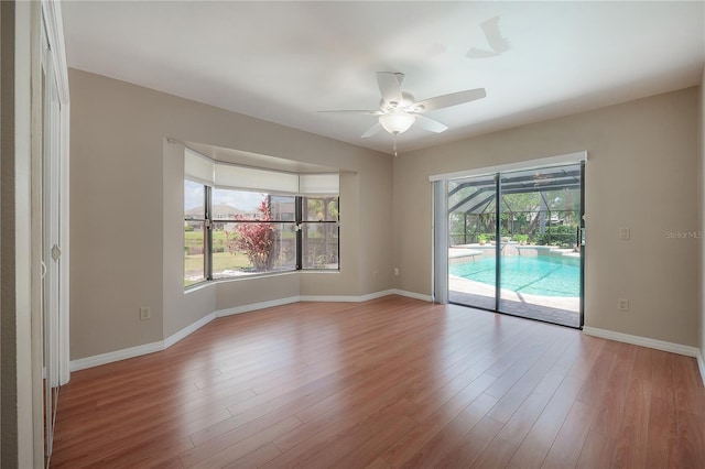 spare room featuring a ceiling fan, baseboards, a wealth of natural light, and wood finished floors