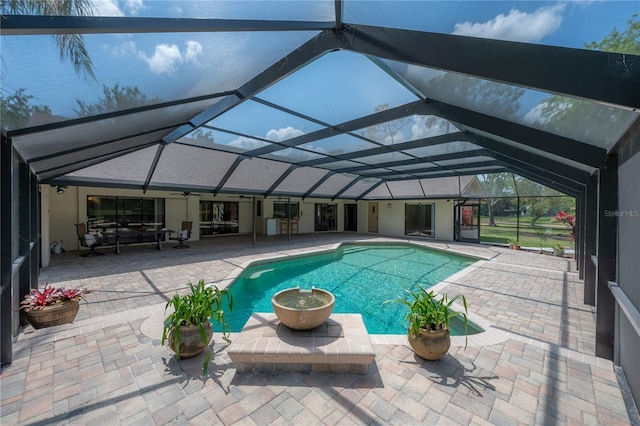 outdoor pool featuring glass enclosure, ceiling fan, and a patio area