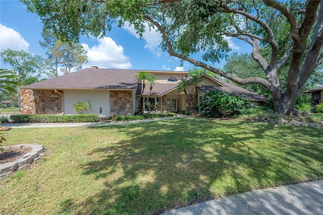 ranch-style house featuring a front lawn, stucco siding, and stone siding