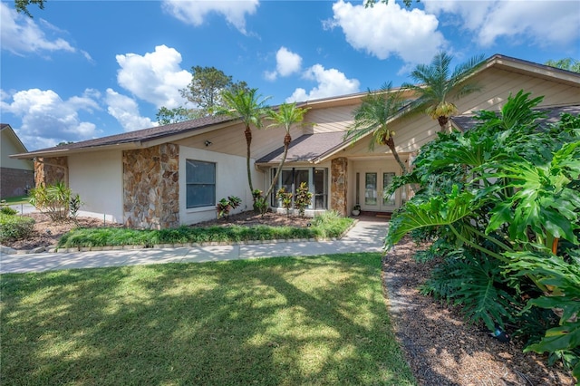 view of front of home featuring a front yard, french doors, stone siding, and stucco siding
