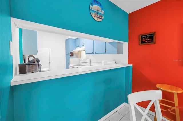 250 Medallion Blvd Unit H, Madeira Beach, FL 33708 - kitchen featuring a peninsula, light tile patterned floors, under cabinet range hood, and white range with electric cooktop
