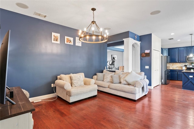 living room featuring visible vents, dark wood-style flooring, baseboards, and a notable chandelier