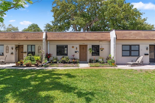 ranch-style house featuring roof with shingles, mansard roof, and a front yard