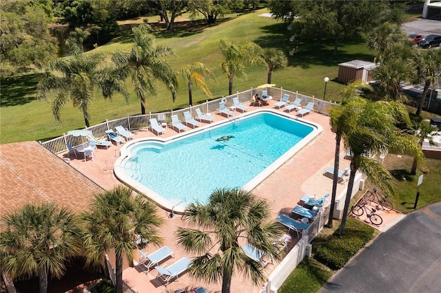 community pool with a patio area, fence, and a yard