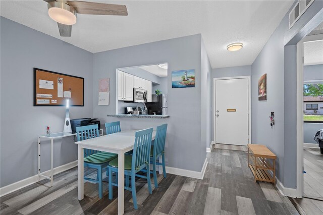 dining space featuring baseboards, a ceiling fan, wood finished floors, and visible vents