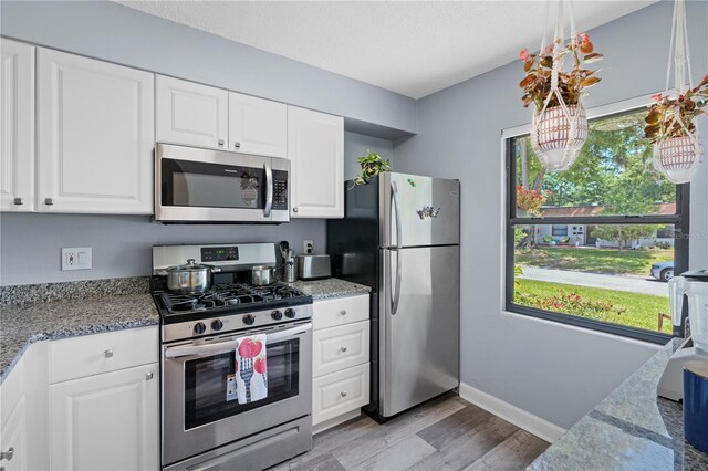 kitchen featuring light wood-style flooring, appliances with stainless steel finishes, a healthy amount of sunlight, and white cabinets