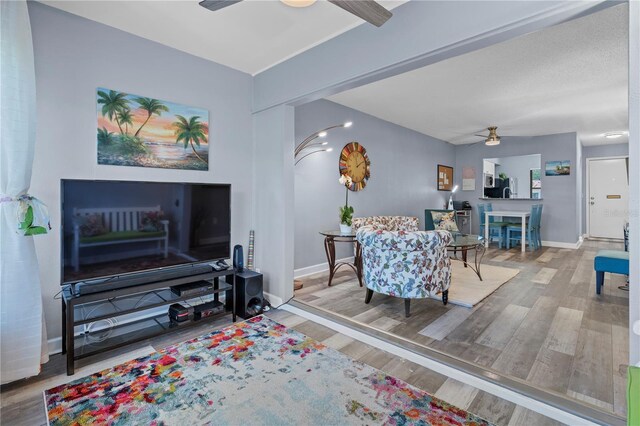 living area featuring baseboards, ceiling fan, and wood finished floors