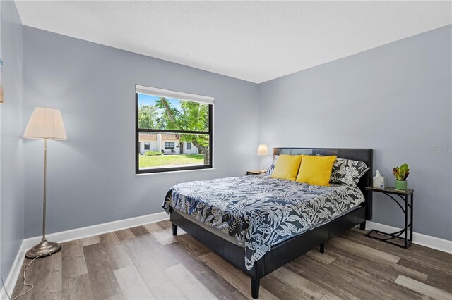 bedroom with baseboards and wood finished floors