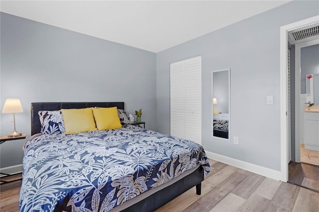bedroom featuring baseboards, wood finished floors, and visible vents