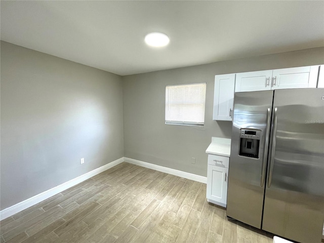 8310 Croton Ave, Tampa, FL 33619 - kitchen with baseboards, stainless steel refrigerator with ice dispenser, light countertops, white cabinets, and light wood-style flooring