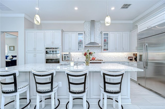 kitchen with white cabinets, stainless steel appliances, decorative backsplash, and wall chimney exhaust hood