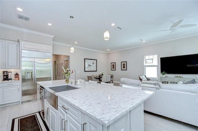 kitchen with visible vents, a kitchen island with sink, open floor plan, a sink, and stainless steel appliances