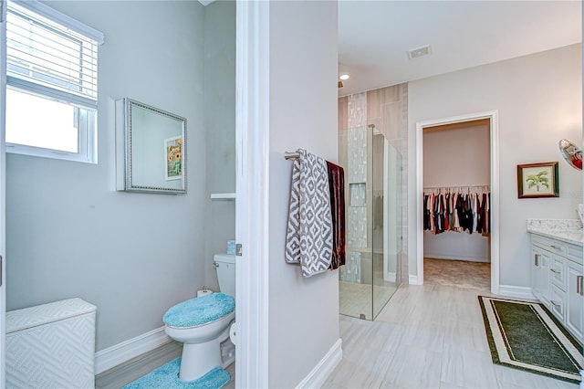 bathroom featuring vanity, visible vents, toilet, baseboards, and a stall shower