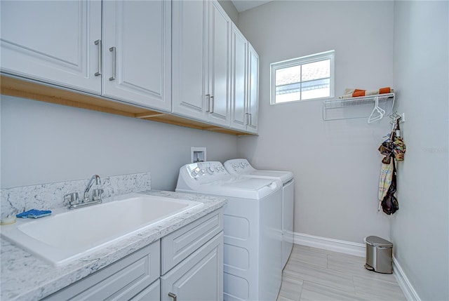 laundry room featuring cabinet space, separate washer and dryer, baseboards, and a sink