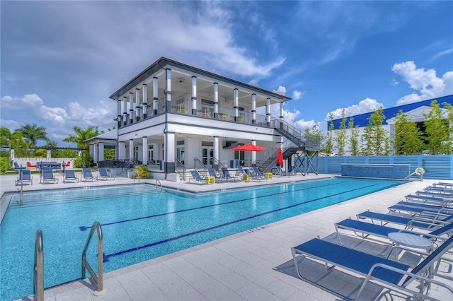 community pool with fence, a patio, and stairway