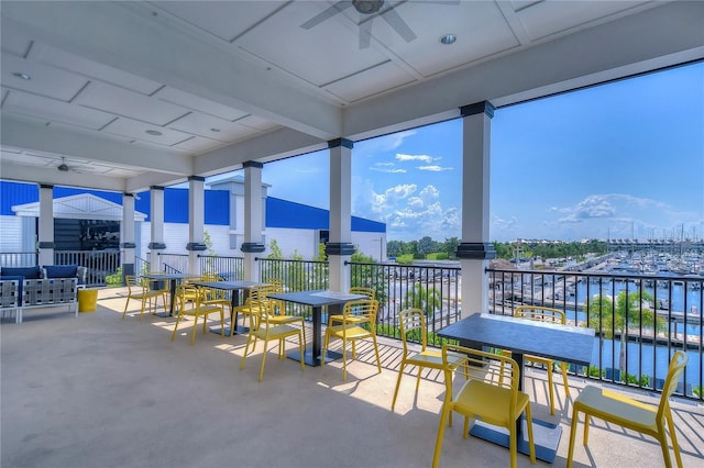 view of patio with a water view, ceiling fan, and a balcony