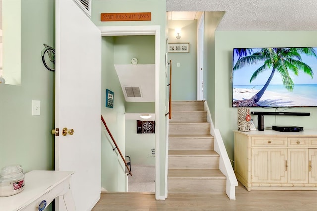 staircase with visible vents and wood finished floors