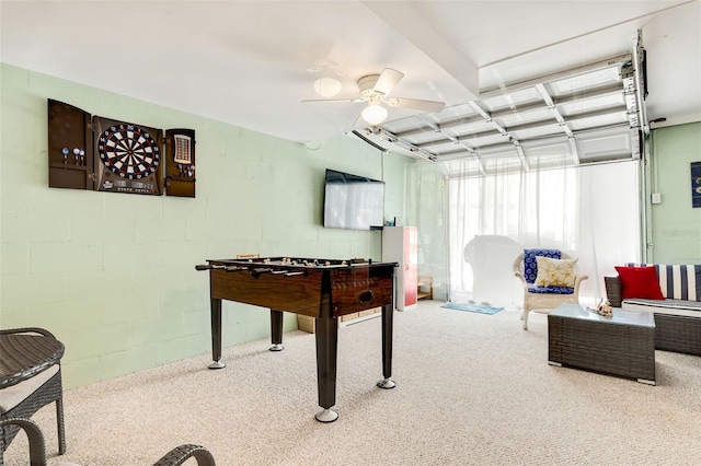 recreation room with a ceiling fan, carpet, and concrete block wall