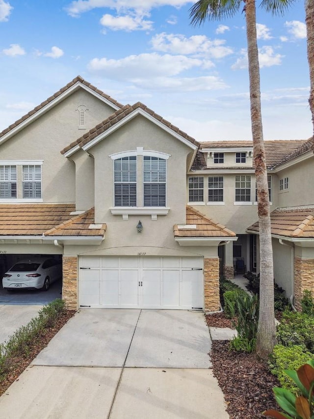 view of front of property featuring a garage, stucco siding, driveway, and stone siding