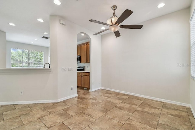 empty room featuring ceiling fan, visible vents, arched walkways, baseboards, and recessed lighting